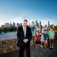 Professor Matthew Sanders in front of a family and the Brisbane skyline
