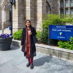 PhD candidate Tania Chatterjee standing in front of a sandstone building at Yale Law School